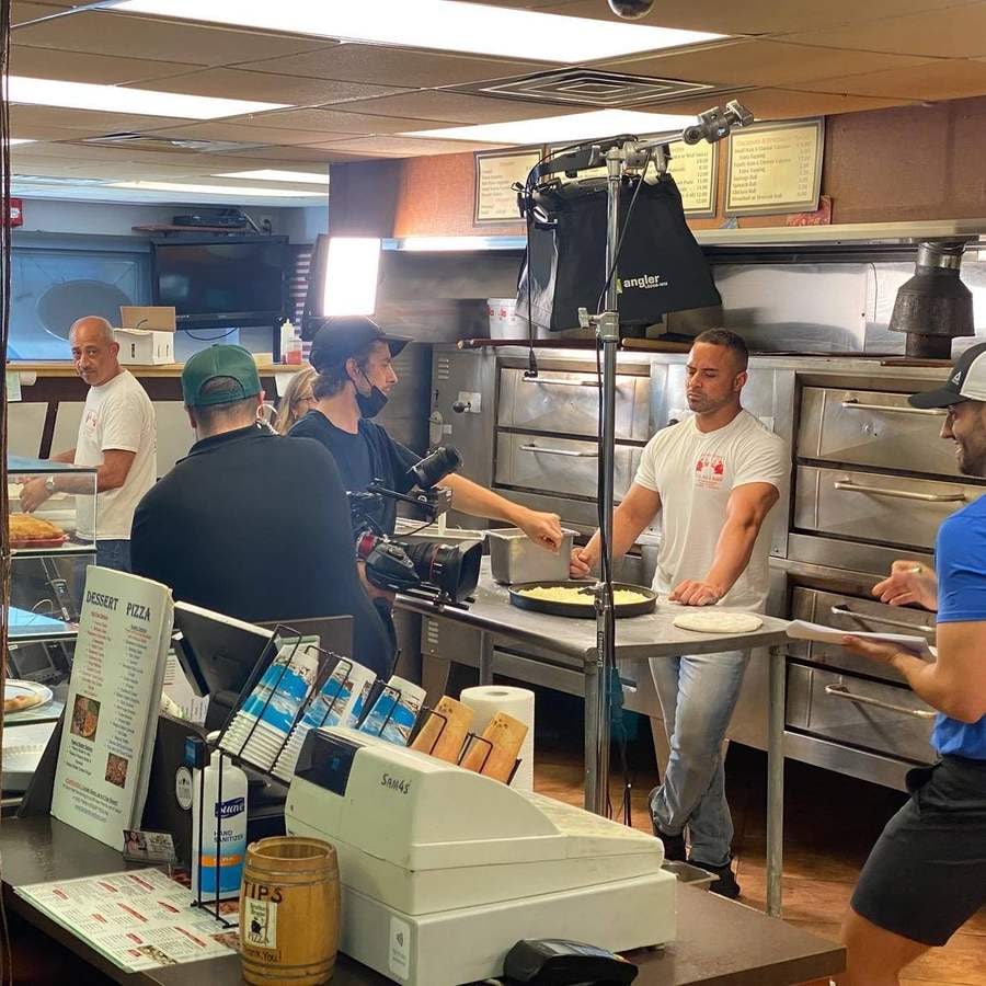 A production crew filming Pietro building a pizza at the shop